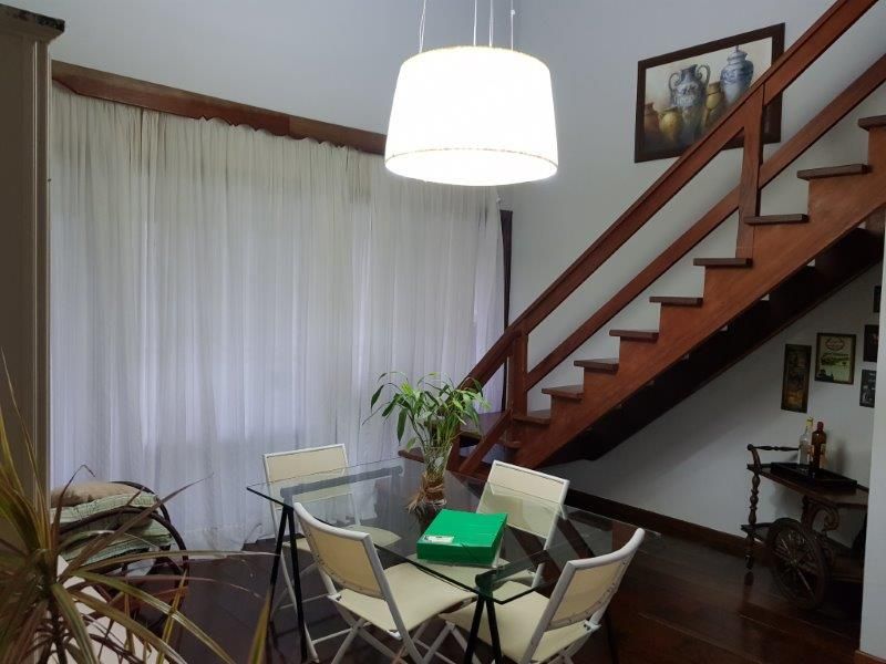 Sala de jantar com pé-direito duplo e escada de madeira